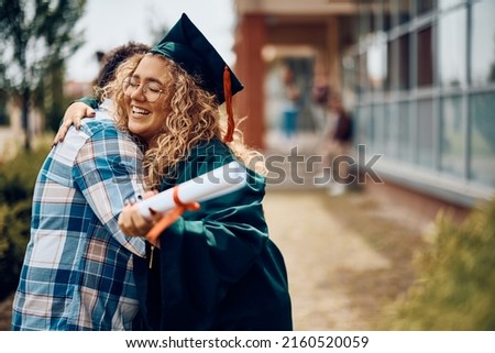 Happy student hugging her father after receiving diploma on graduation day at the university.