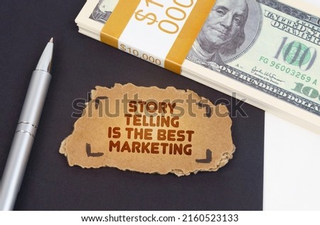Business concept. On the table are dollars, a pen and a cardboard sign with the inscription - Story telling is the best marketing
