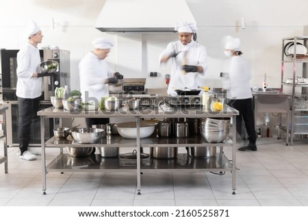 Chef cooks working in professional kitchen. Chefs hurry up, actively cooking meals for restaurant. Long exposure with motion blurred figures Royalty-Free Stock Photo #2160525871