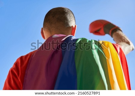 Lgbt fight concept. Male with boxing blog and lgbtq flag raises arm on sunny morning Royalty-Free Stock Photo #2160527891