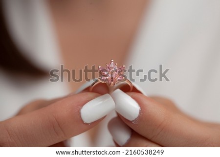 Silver flower ring on a woman's hand in a white dress with white nail polish. Jewelry image for e-commerce, online selling and social media.