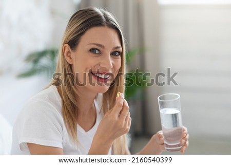 Healthy lifestyle, vitamins and minerals, supplements in diet concept. Smiling pretty young woman taking pill after waking up, holding gelatin capsule and glass of water, copy space Royalty-Free Stock Photo #2160540399