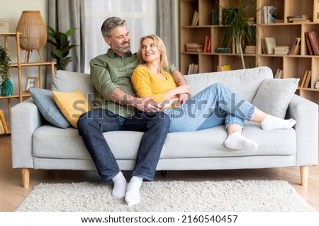 Romantic happy middle aged couple relaxing on couch at home, smiling loving mature spouses resting in cozy living room interior, embracing on sofa, enjoying weekend time together, copy space Royalty-Free Stock Photo #2160540457