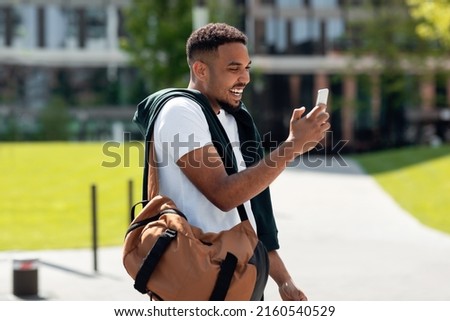 Modern Communication. Cheerful happy African American guy holding smart phone making video call on cell, talking with friends or taking photo, blogger recording video for vlog in social media network
