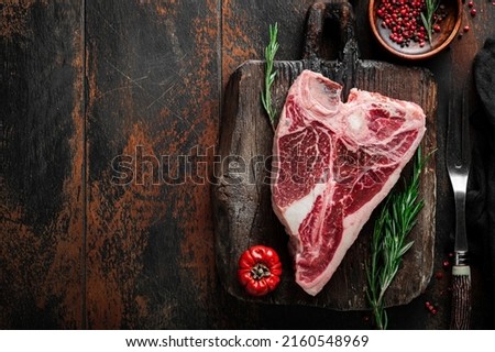 Raw T-Bone steak of premium beef on wooden board prepared for cooking with herbs and spices, top view and copy space Royalty-Free Stock Photo #2160548969