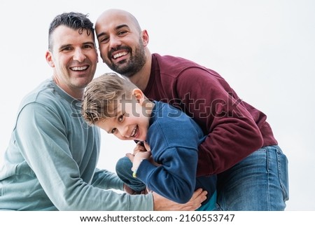 Gay fathers and son having fun together outdoor - LGBT diversity family love concept - Focus on left man face Royalty-Free Stock Photo #2160553747