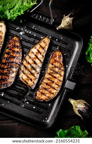 Pieces of eggplant grilled in a grill pan. On a wooden background. High quality photo