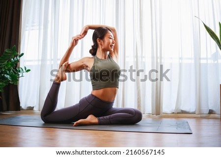 Asian woman in sports clothing doing yoga at home to quarantine herself from Covid-19, New normal lifestyle concept. Healthy lifestyle. Relaxing at home Royalty-Free Stock Photo #2160567145