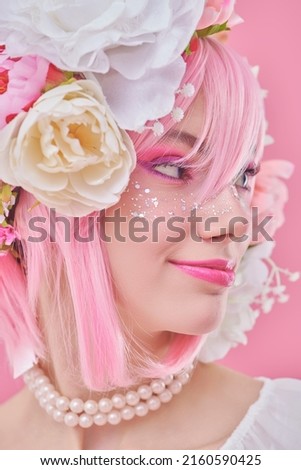 A lovely smiling girl with bright pink makeup and pink hair with floral wreath on her head. Spring and summer beauty. Japanese anime style. Pink background. Beauty girl. 