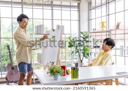 Young carefree gay couple drawing painting using colorful rainbow colors creating modern beautiful artwork, LGBT community people.