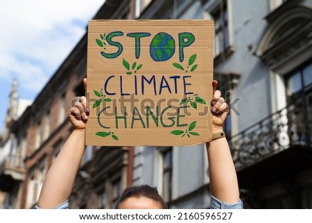 Protester holding sign Stop Climate Change. Woman with placard at protest rally demonstration, strike against global warming.