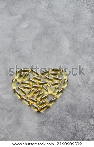 Heart-shaped omega-3 capsules on a gray background. The concept of medicine and healthy living. Top view.