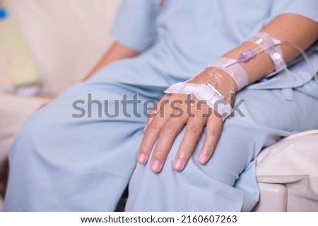 Hands patient woman receiving saline solution during sitting on sick bed at hospital Royalty-Free Stock Photo #2160607263