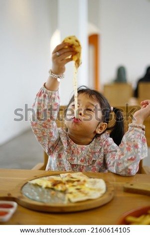 A kid enjoy pizza with cheese