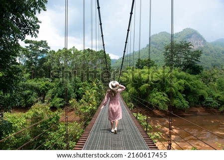 woman traveller is travelling at Rope Bridge Khao Pung or Rope Bridge Thep Pitak with a shape that looks like a heart near Ratchaprapha dam Khao sok national park at suratthani,Thailand. Royalty-Free Stock Photo #2160617455