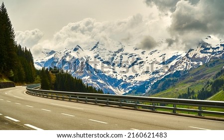 Cloudy Dachstein mountains in Austria with the high alpine road in the foreground during a road trip through the Alps Royalty-Free Stock Photo #2160621483