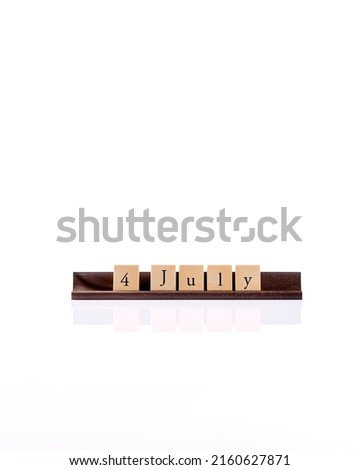 word 4 July spelled out on wooden tiles on a rack on white background textured for banner design