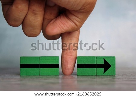 Finger divides the arrow cubes into two parts. Interruption, slowing down process, sabotage concept Royalty-Free Stock Photo #2160652025