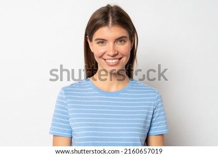 Pretty joyful female with fair hair, dressed casually in blue clothes matching with color of her eyes, looking at camera with candid happy smile isolated over white blank studio wall Royalty-Free Stock Photo #2160657019