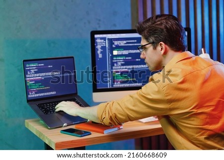 Back rear side profile view young data scientist software engineer IT specialist programmer man wearing shirt work at home writing typing code script on laptop pc computer. Game development concept