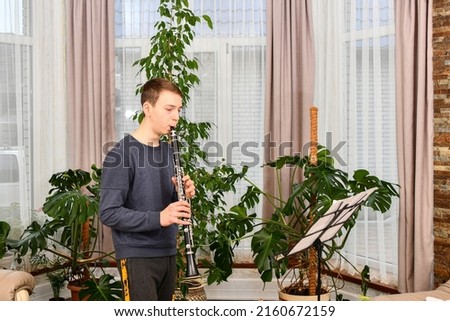 The teenager diligently plays the clarinet. Learning music at home.