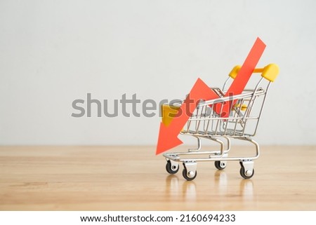 Shopping trolley with red chart falling down on wooden table background copy space. Economic recession crisis, core retail sales decrease, inflation, goods price up, food shortage concept. Royalty-Free Stock Photo #2160694233