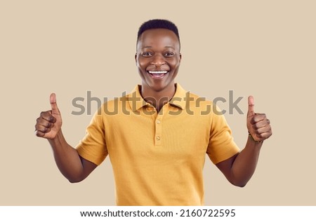 Overjoyed African American man customer isolated on brown studio background show thumbs up give recommendation. Smiling biracial male client laugh recommend good quality service. Royalty-Free Stock Photo #2160722595