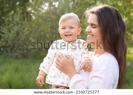 Happy mother with her cute baby in park on sunny day, space for text