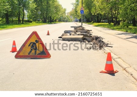 Construction road sign and orange traffic cones. Preparation for laying new asphalt pavement. Road repair and rodework concept. Traffic cones on a street as a warning sign.