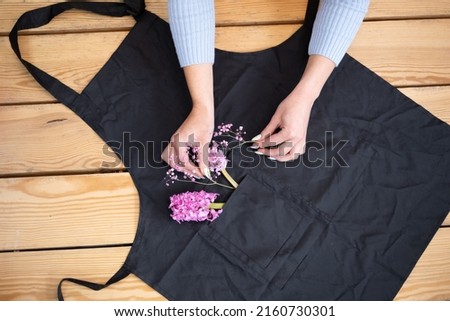 pink flowers on a black apron on a wooden background. Florist concept, top view