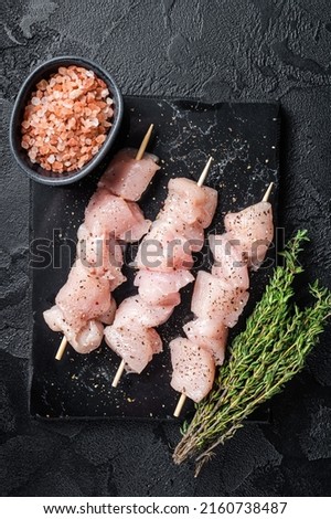 Raw chicken meat shish kebab skewers. Black background. Top view.