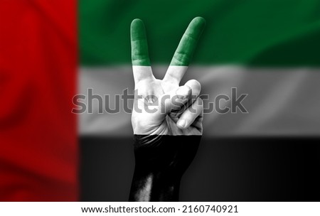 Hand making the V victory sign with flag of uae