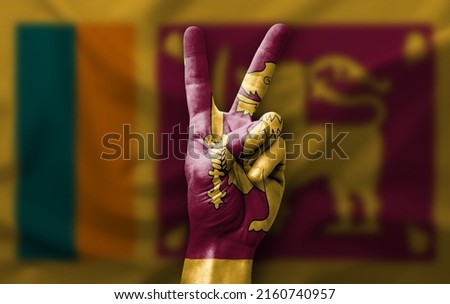 Hand making the V victory sign with flag of sri lanka