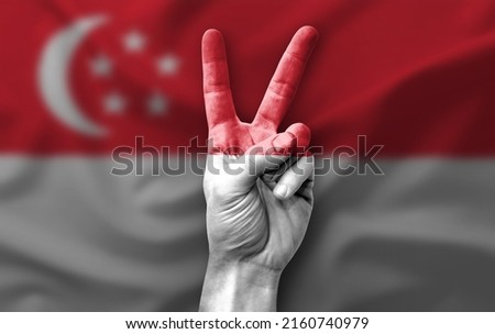 Hand making the V victory sign with flag of singapore