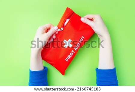 First Aid Kit in female hands on a green background.