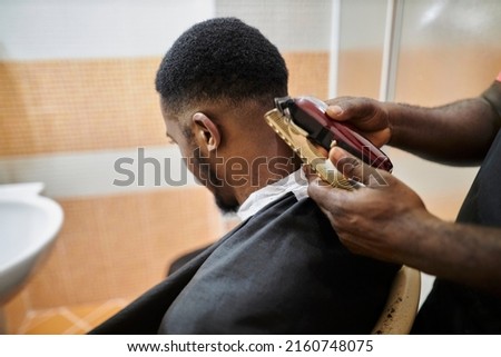 african american hairdresser cuts an african american man's hair with a clipper. clipper haircut Royalty-Free Stock Photo #2160748075