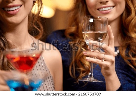 celebration, bachelorette party and holidays concept - happy women drinking wine and and cocktails at night club