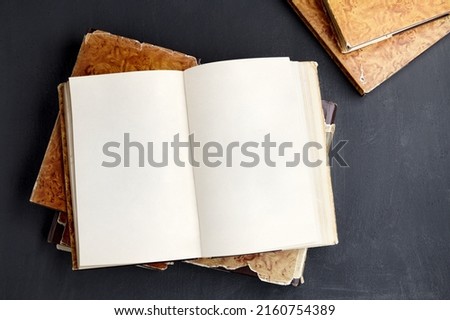 Open vintage book or notebook in a dust jacket on a stack of old shabby books Royalty-Free Stock Photo #2160754389