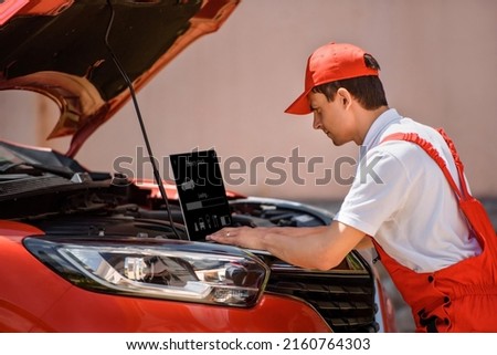 Young man car mechanic electrician is using an laptop computer to check diagnostic the car errors and problems and fix it. 
 Royalty-Free Stock Photo #2160764303