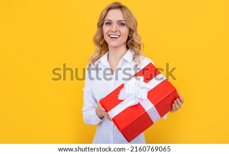 positive woman with big present box on yellow background