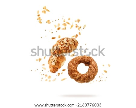 Fresh baked turkish simit sesame bagel, french butter almond nut croissants flying falling with seeds, flakes and crumbs isolated on white background. Pastry shop card Royalty-Free Stock Photo #2160776003