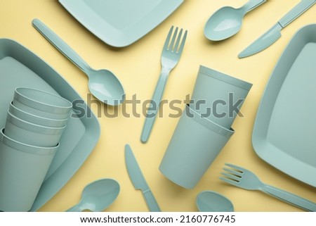 Bright plastic reusable tableware on a yellow background. Top view Royalty-Free Stock Photo #2160776745