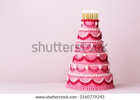 Extravagant pink tiered birthday cake decorated with vintage buttercream piped frills and gold birthday candles Royalty-Free Stock Photo #2160779243