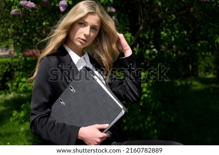 Beautiful blonde girl holding documents and preparing for business presentation in technology company. Stylish young woman in business suit. High quality photo.