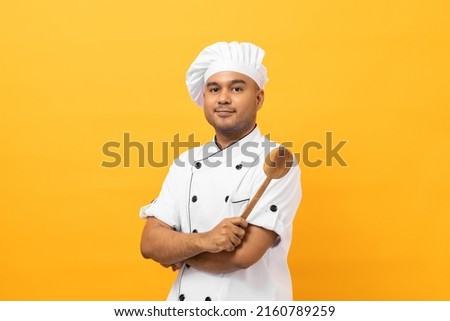 Young handsome asian man chef in uniform with hat holding ladle utensils cooking in the kitchen various gesture action on isolated yellow background. Indian man Occupation chef restaurant and hotel. Royalty-Free Stock Photo #2160789259