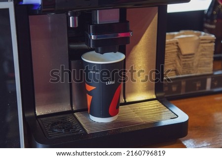A cardboard cup of coffee is prepared using a coffee machine at a gas station. Royalty-Free Stock Photo #2160796819