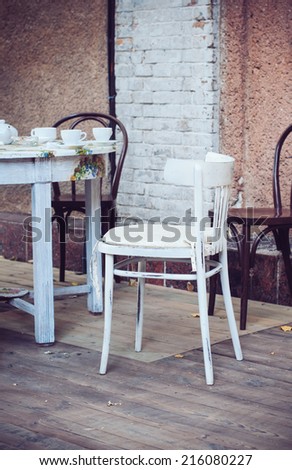 Wooden coffee table and chairs on the terrace of an outdoor cafe in a European city.