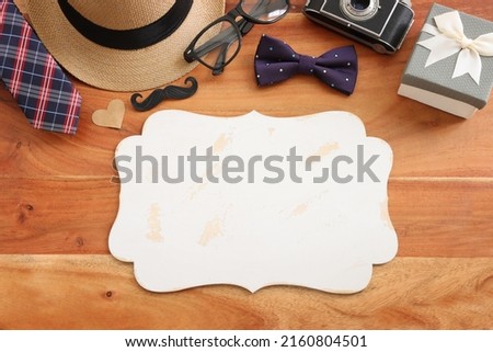 Father's day concept. bow tie, fedora hat, glasses, old photo camera and funny moustache over wooden background. top view, flat lay