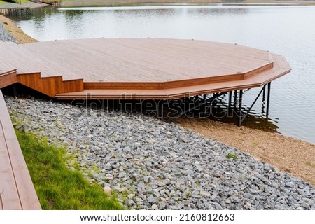 Wooden pier on a pond in the city park, a place to relax by the water, equipped access to the lake, a parking area for boats, a pier on the river, an embankment in the city. High quality photo