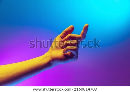 Studio shot of aethentic human hand isolated on gradient purple-blue background in neon light. Concept of human relation, community, art, symbolism, culture and history